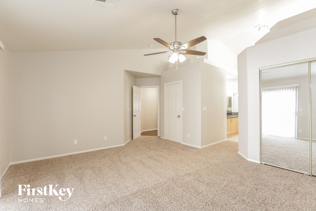 a spacious living room with carpet and a ceiling fan