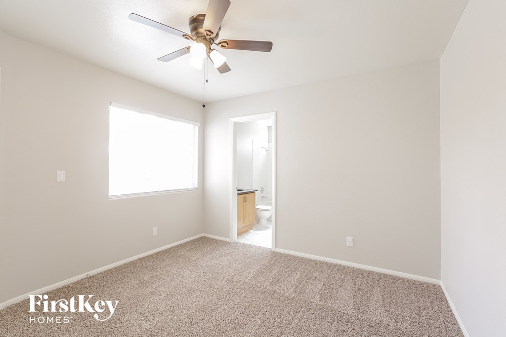 a living room with a ceiling fan and a carpet