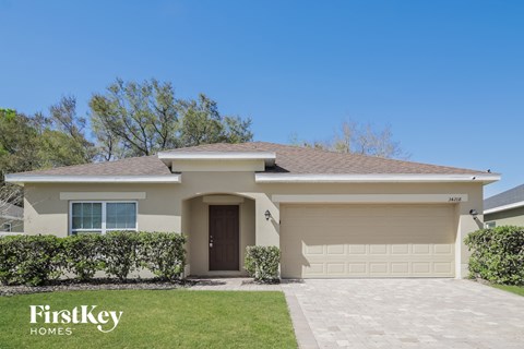 a beige house with a garage door and a lawn