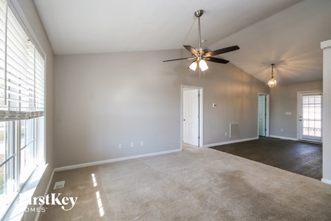 A spacious room with a ceiling fan and carpeted floor.