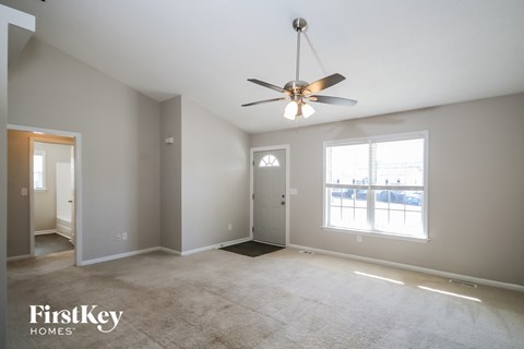 A spacious room with a ceiling fan and a large window.