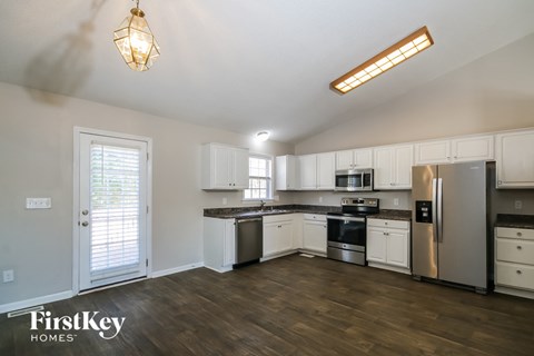A kitchen with white cabinets and a wooden floor.