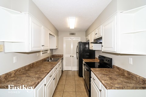 A kitchen with granite countertops and white cabinets.