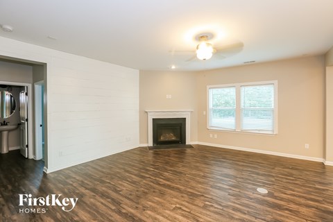 A spacious living room with a fireplace and wood flooring.