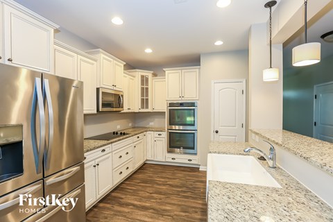 A kitchen with a stainless steel refrigerator and wooden floors.