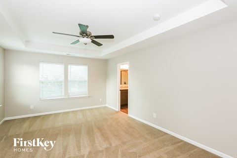 A spacious room with a fan and a door in the background.