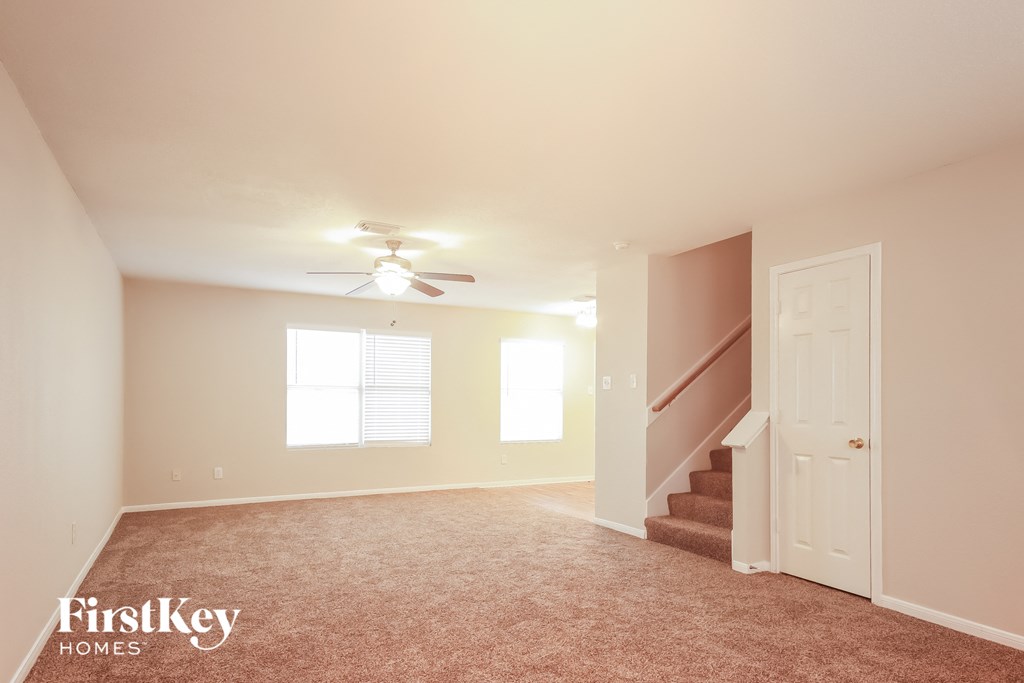 a living room with carpeted stairs and a ceiling fan