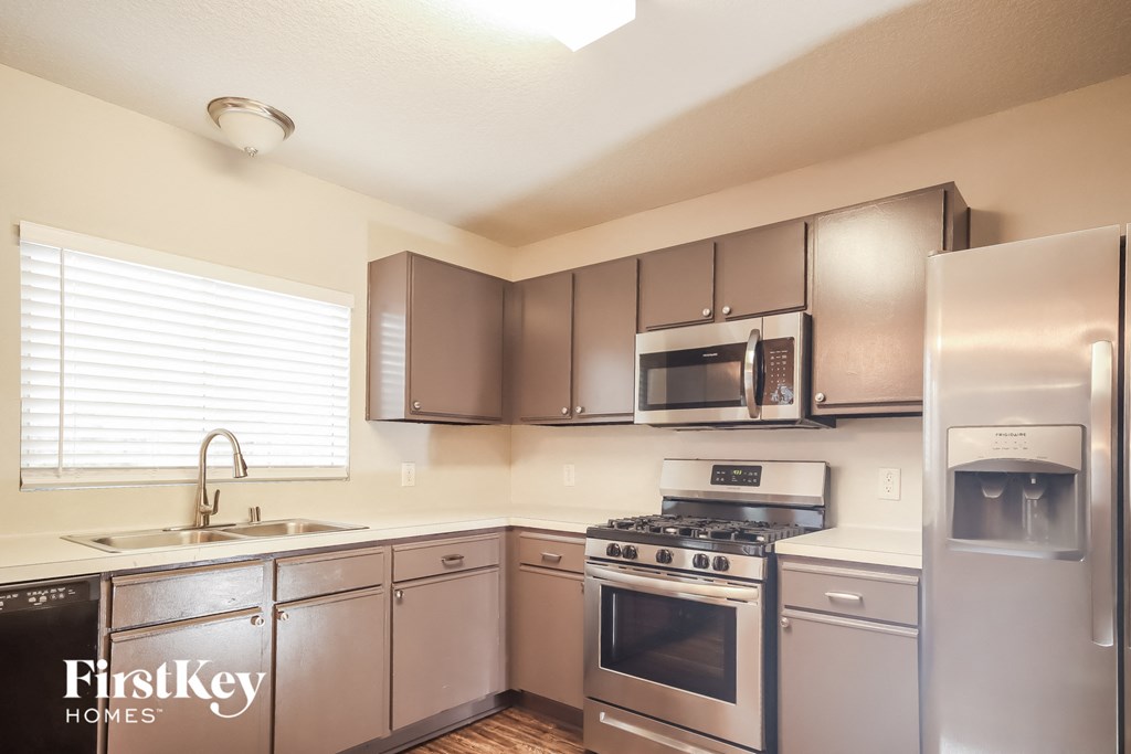 an empty kitchen with stainless steel appliances and a window