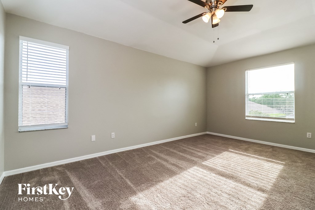 an empty living room with carpet and a ceiling fan