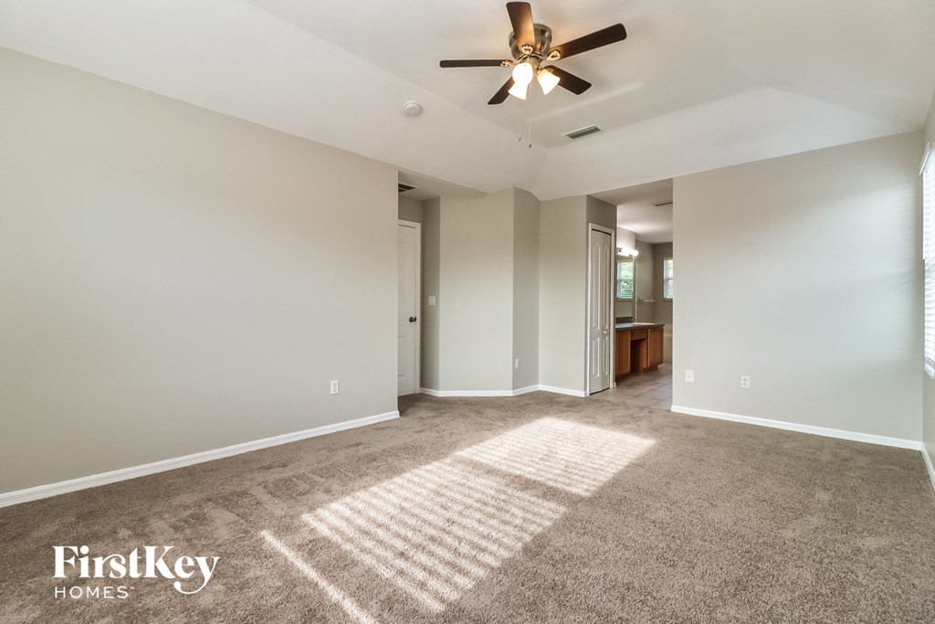 an empty living room with carpet and a ceiling fan