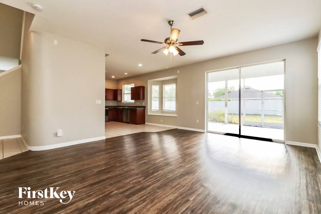 an empty living room with wood floors and a ceiling fan