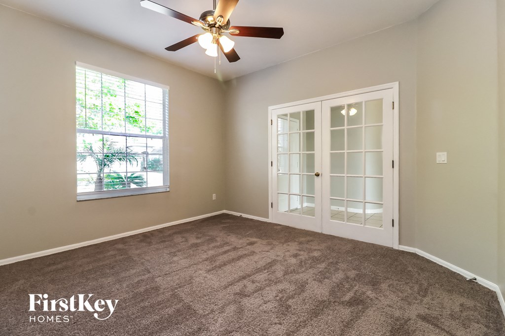 an empty living room with a ceiling fan and a window