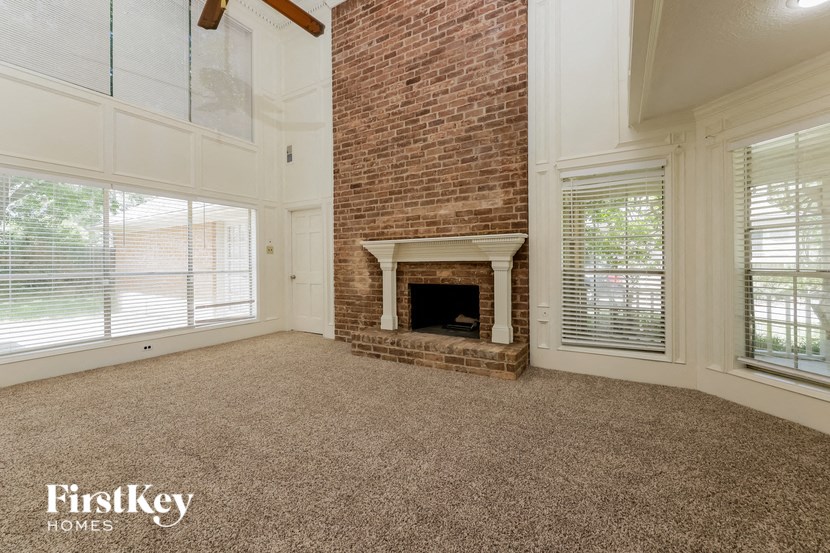 a living room with a brick fireplace and a carpeted floor
