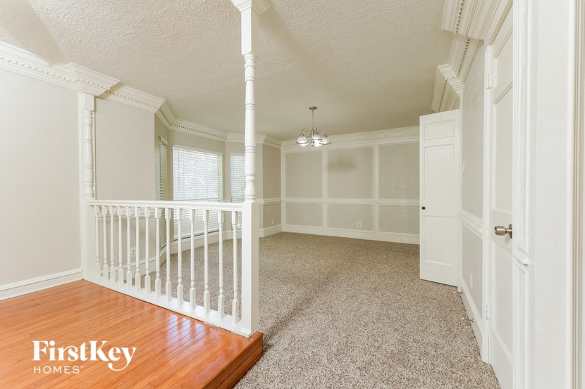 an empty hallway with a white staircase and a wood floor