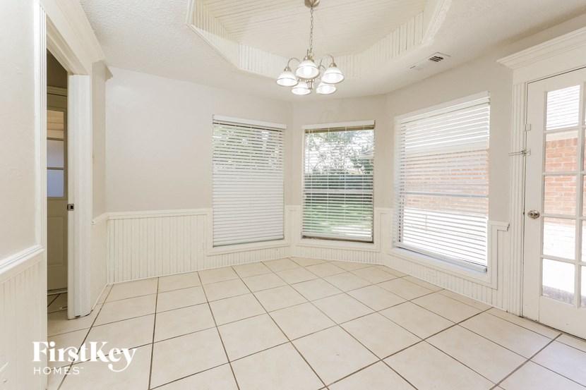 an empty living room with three windows and a tiled floor