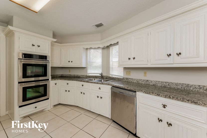 a large kitchen with white cabinets and granite counter tops
