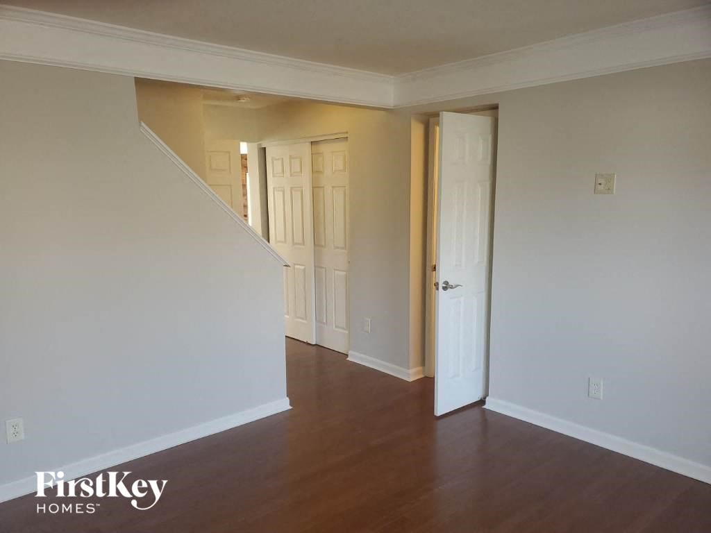 A room with wooden floors and white walls, with a staircase leading to another room.