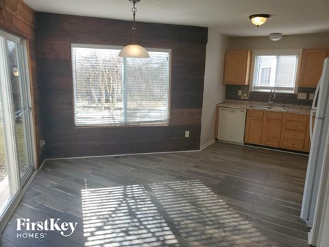 A kitchen with wooden cabinets and a grey floor.