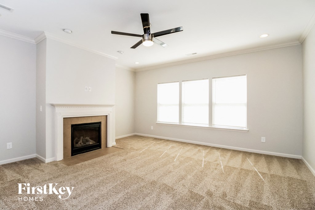A spacious living room with a fireplace and a fan.