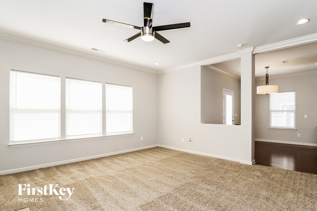 A spacious room with a ceiling fan and large windows.