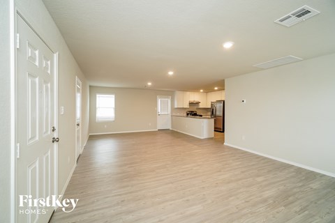A spacious, empty room with wooden floors and white walls.