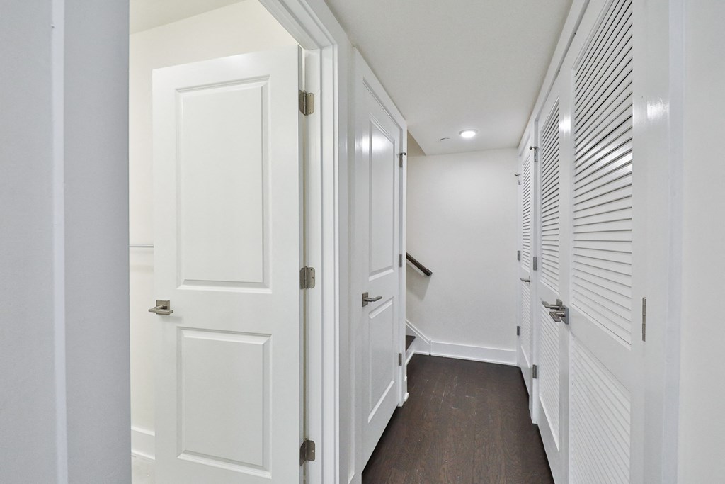 a hallway with white closets and doors and a wood floor