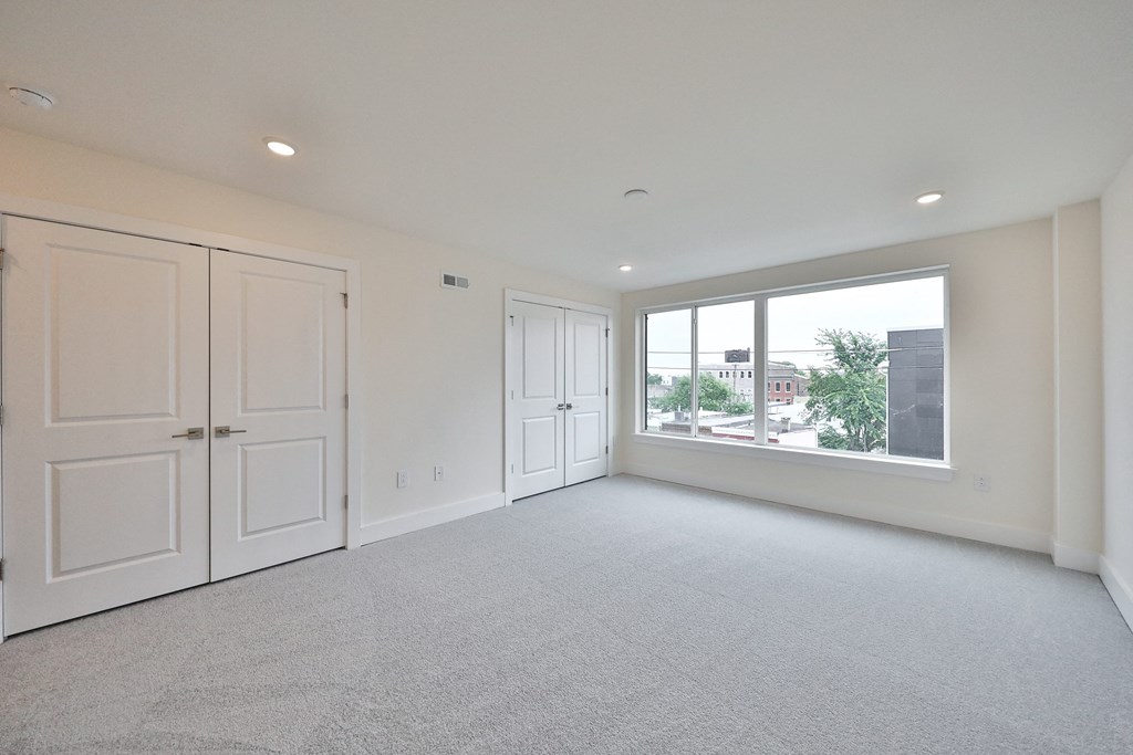 an empty living room with white walls and a large window