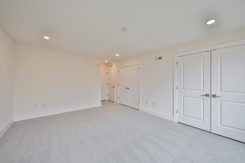 a bedroom with white closets and white carpeting and white doors