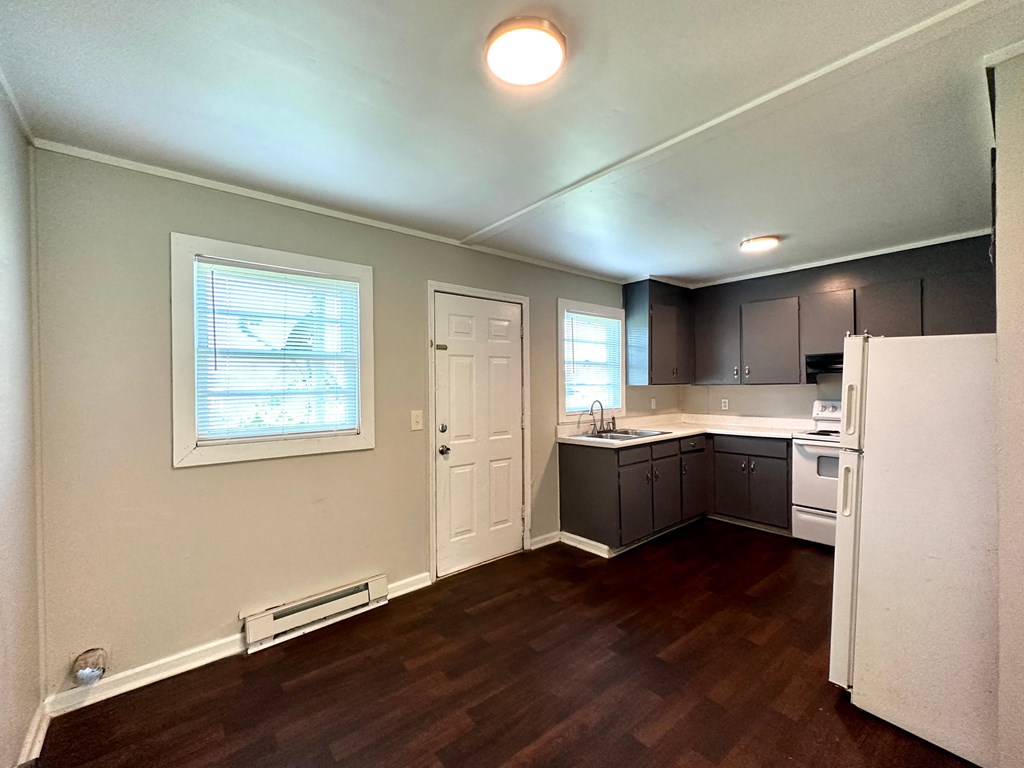 an empty kitchen with white appliances and black cabinets