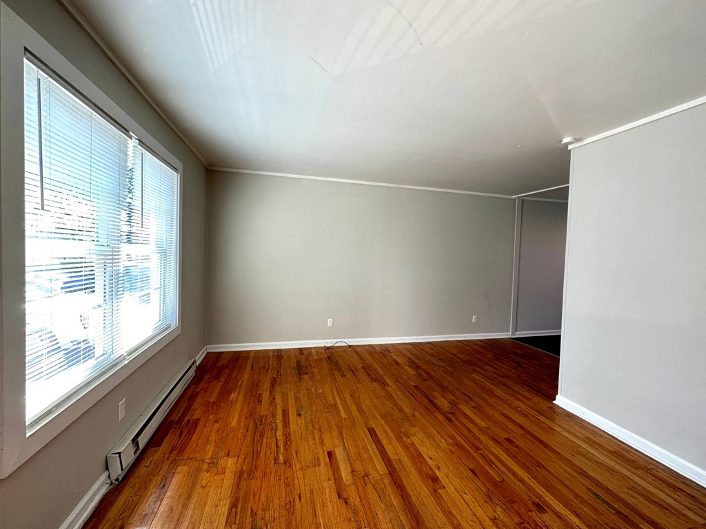 an empty living room with wood floors and a large window