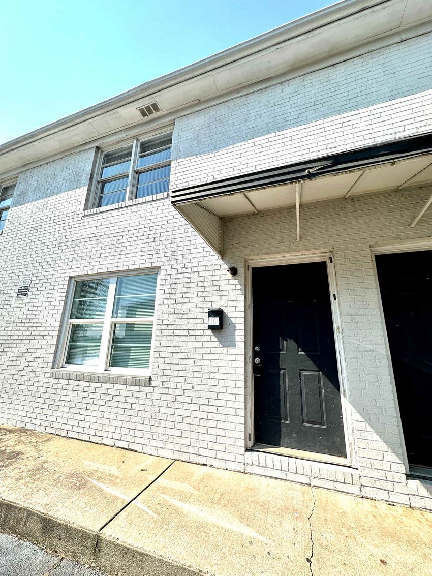the front of a white brick house with a black door