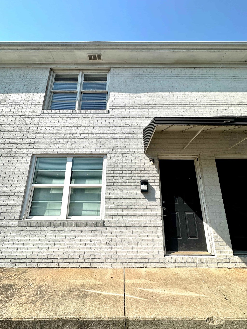 a white brick building with a black door and windows
