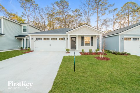 a blue and white house with a driveway and lawn