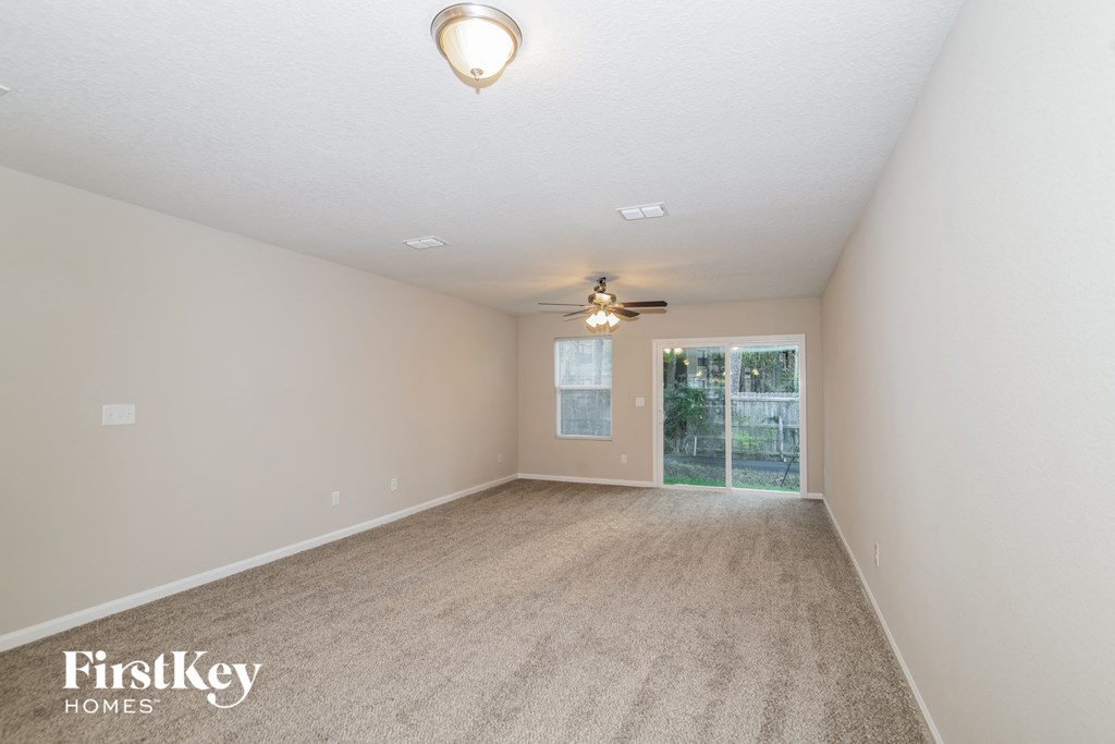 an empty living room with a ceiling fan and a window