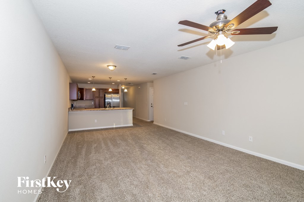 a spacious living room with a ceiling fan and a kitchen