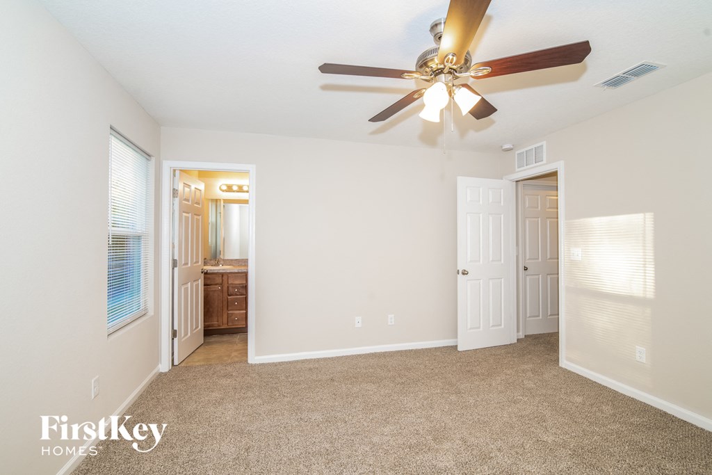 a bedroom with a ceiling fan and a door to a bathroom