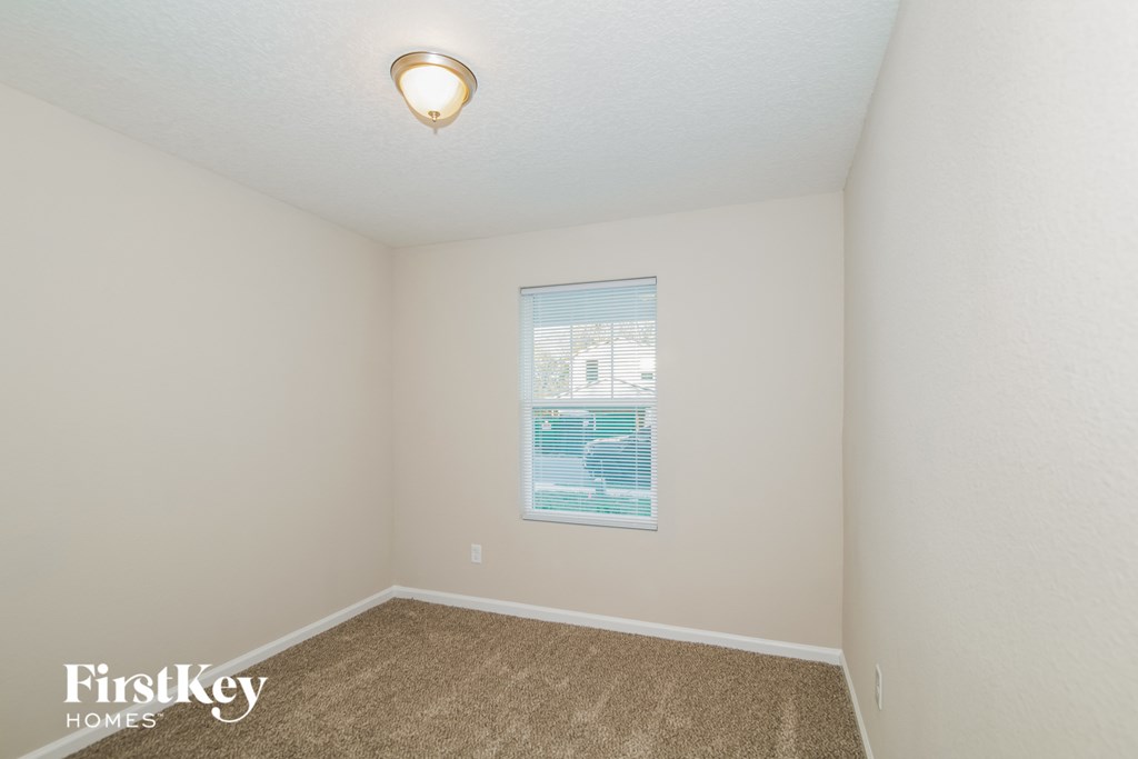 a bedroom with beige carpet and a window