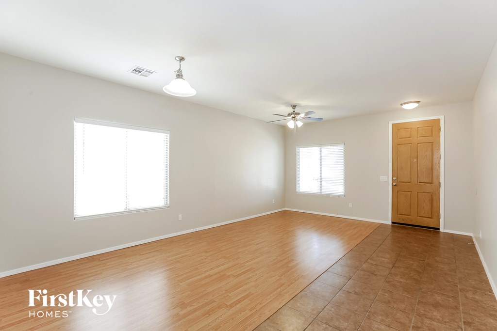 an empty living room with wood flooring and a ceiling fan