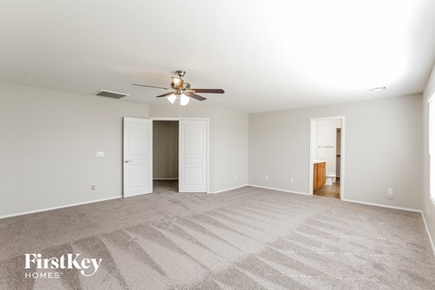 a spacious living room with carpet and a ceiling fan