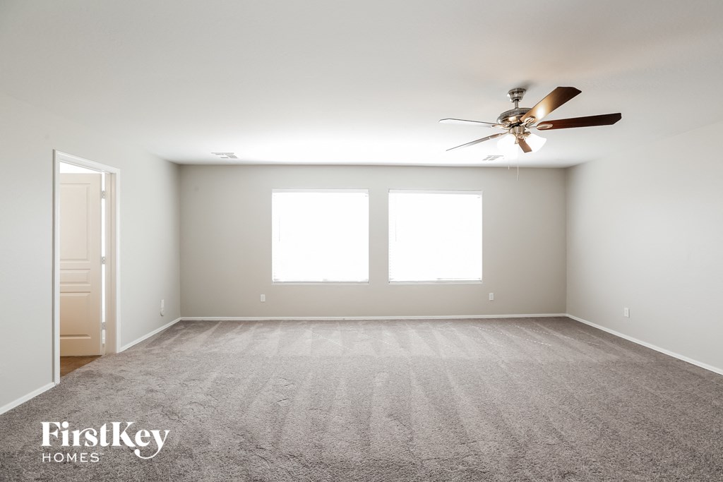 an empty room with a ceiling fan and two windows