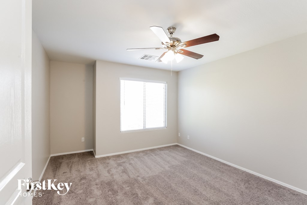 an empty room with a ceiling fan and a window