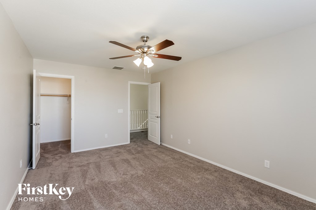 a spacious living room with carpet and a ceiling fan