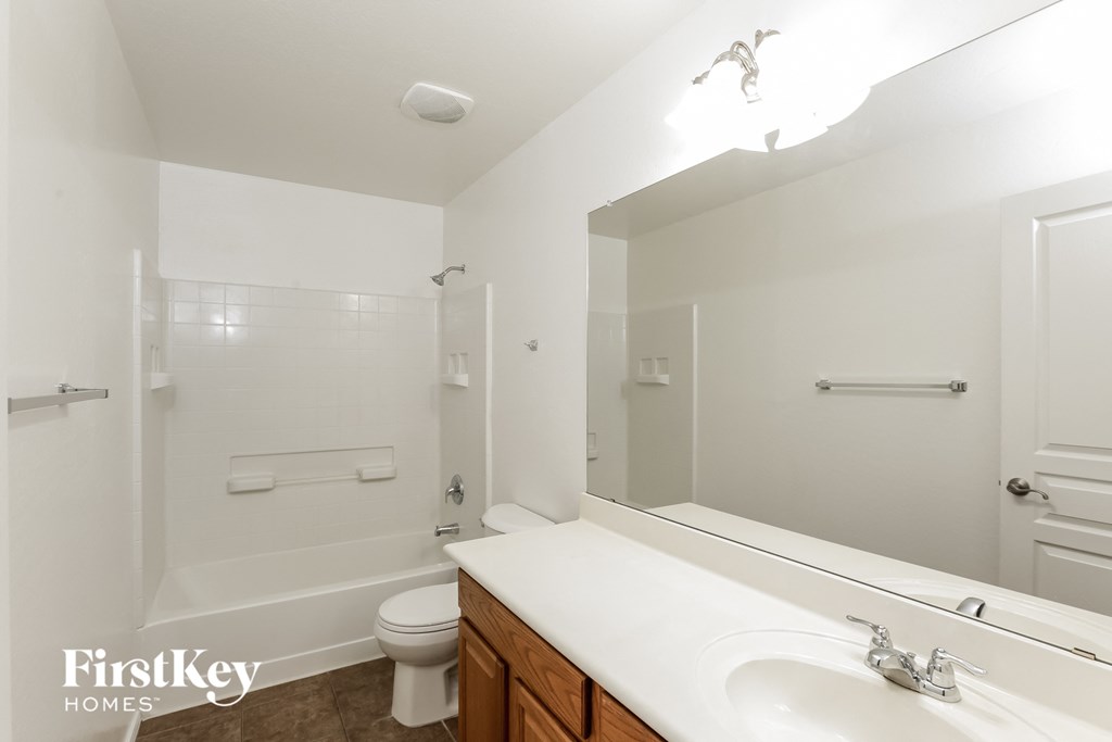 a white bathroom with a large mirror and a white toilet and sink