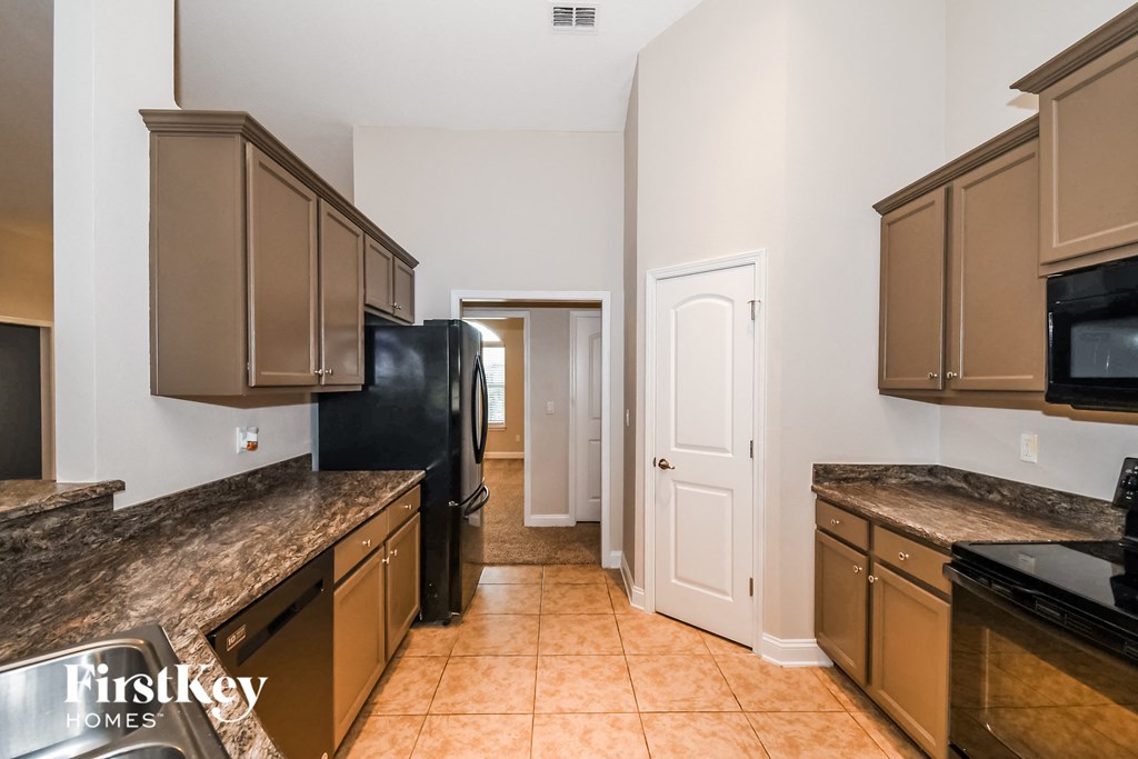 a kitchen with brown cabinets and black appliances and a black refrigerator