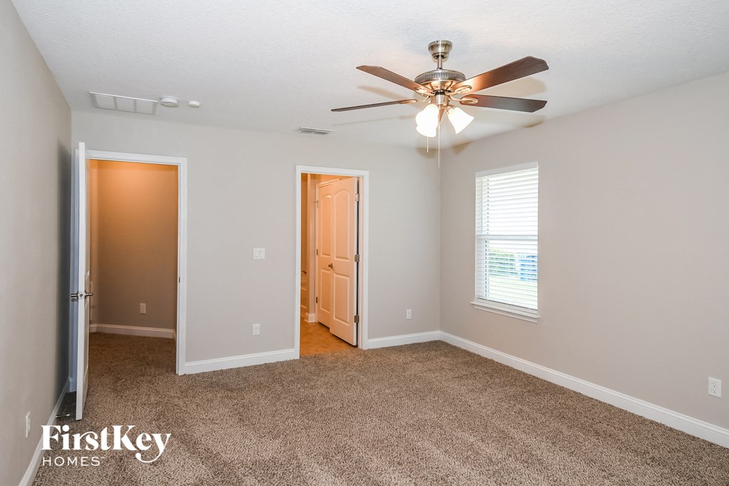 a bedroom with a ceiling fan and a door to a closet