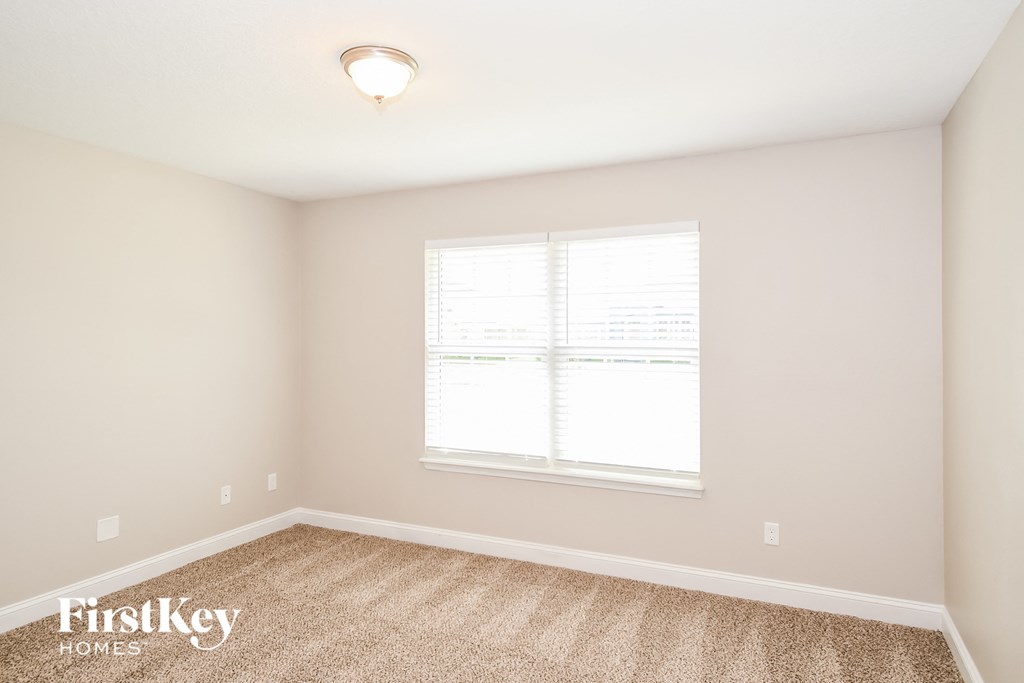 a bedroom with a large window and a carpeted floor