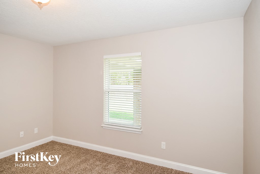 a bedroom with a carpeted floor and a window