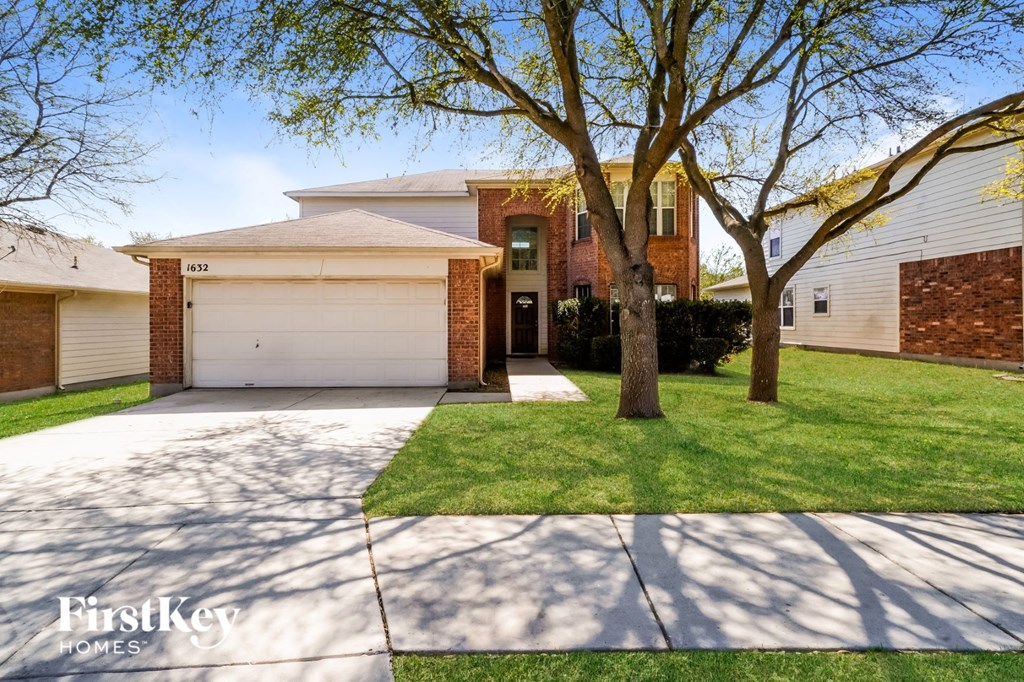 A house with a garage and a tree in front of it.