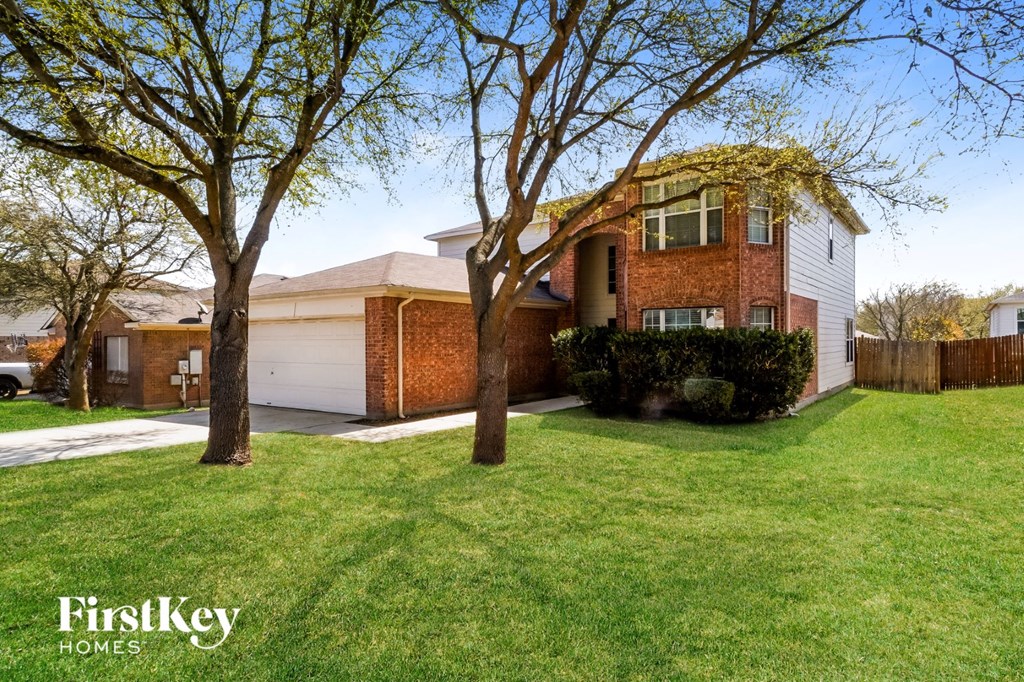 A house with a green lawn and trees in front of it.