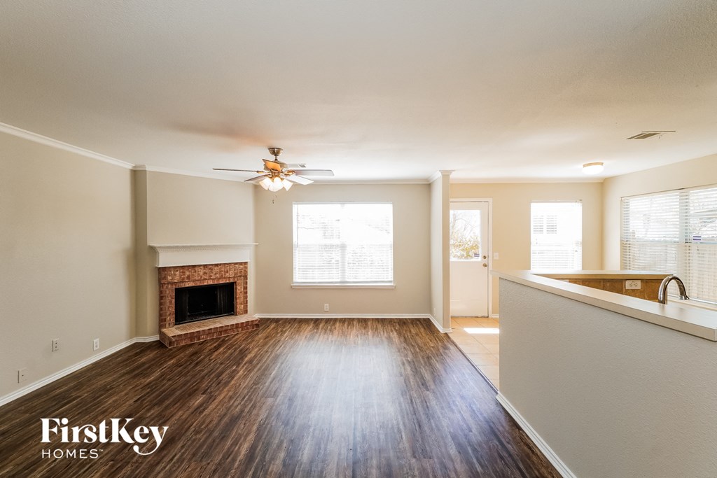 A spacious living room with wood flooring and a fireplace.